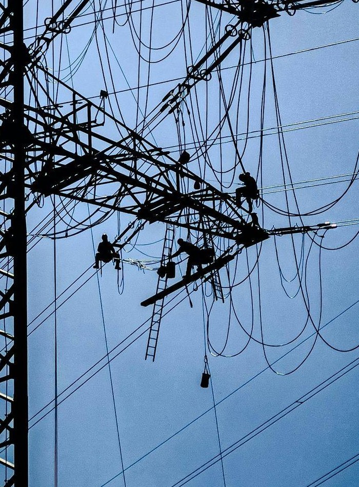 Rope-access crew working at height on a steel lattice transmission tower